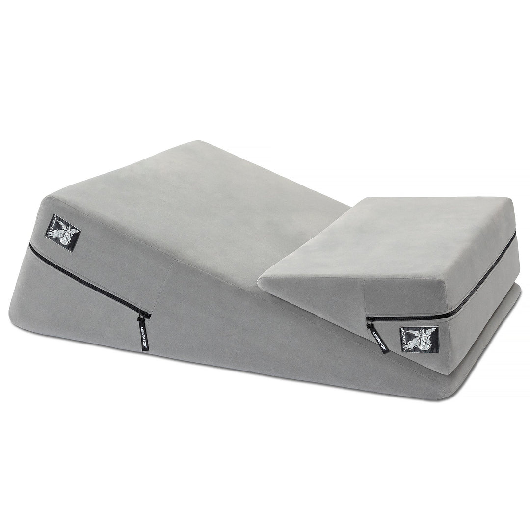 Gray wedge-shaped lounging cushion with zippered pocket and small rectangular logo patch