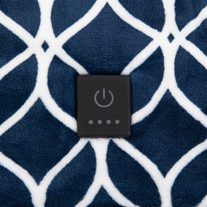 Close-up of the heating control button on a navy plush throw with a white trellis pattern.