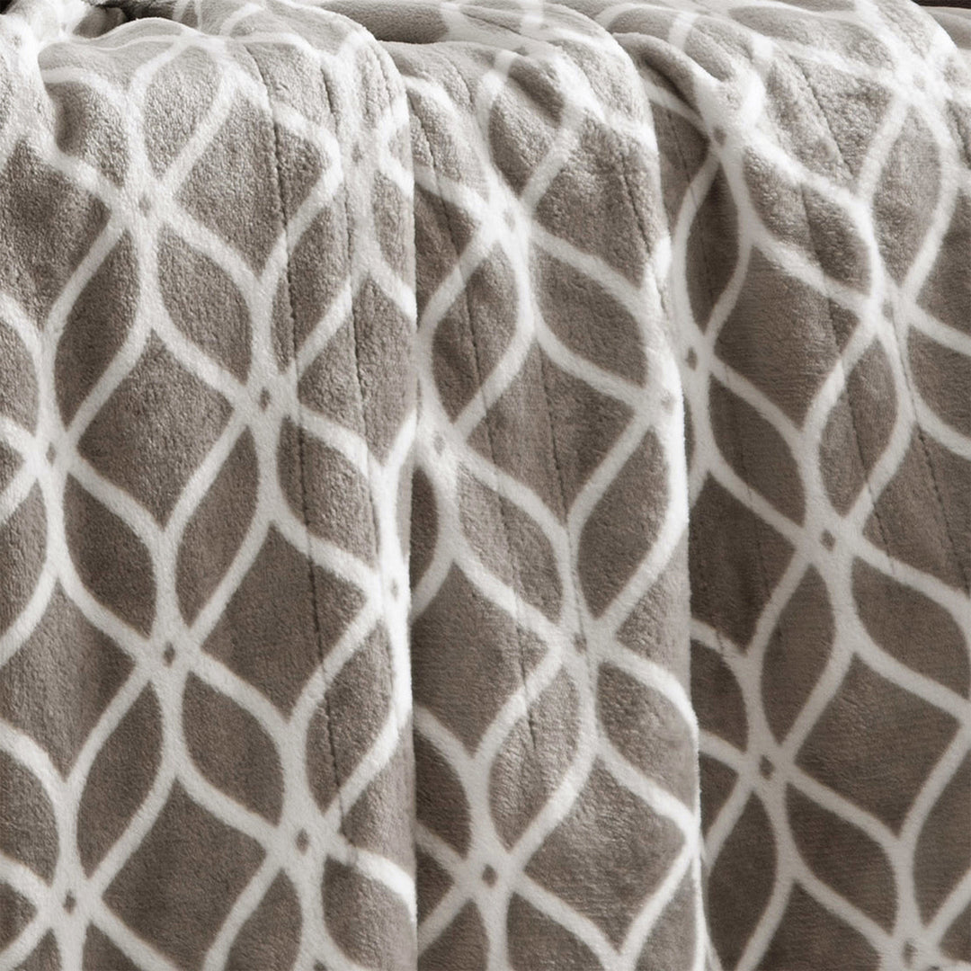 Close-up of taupe heated plush throw with white trellis pattern.
