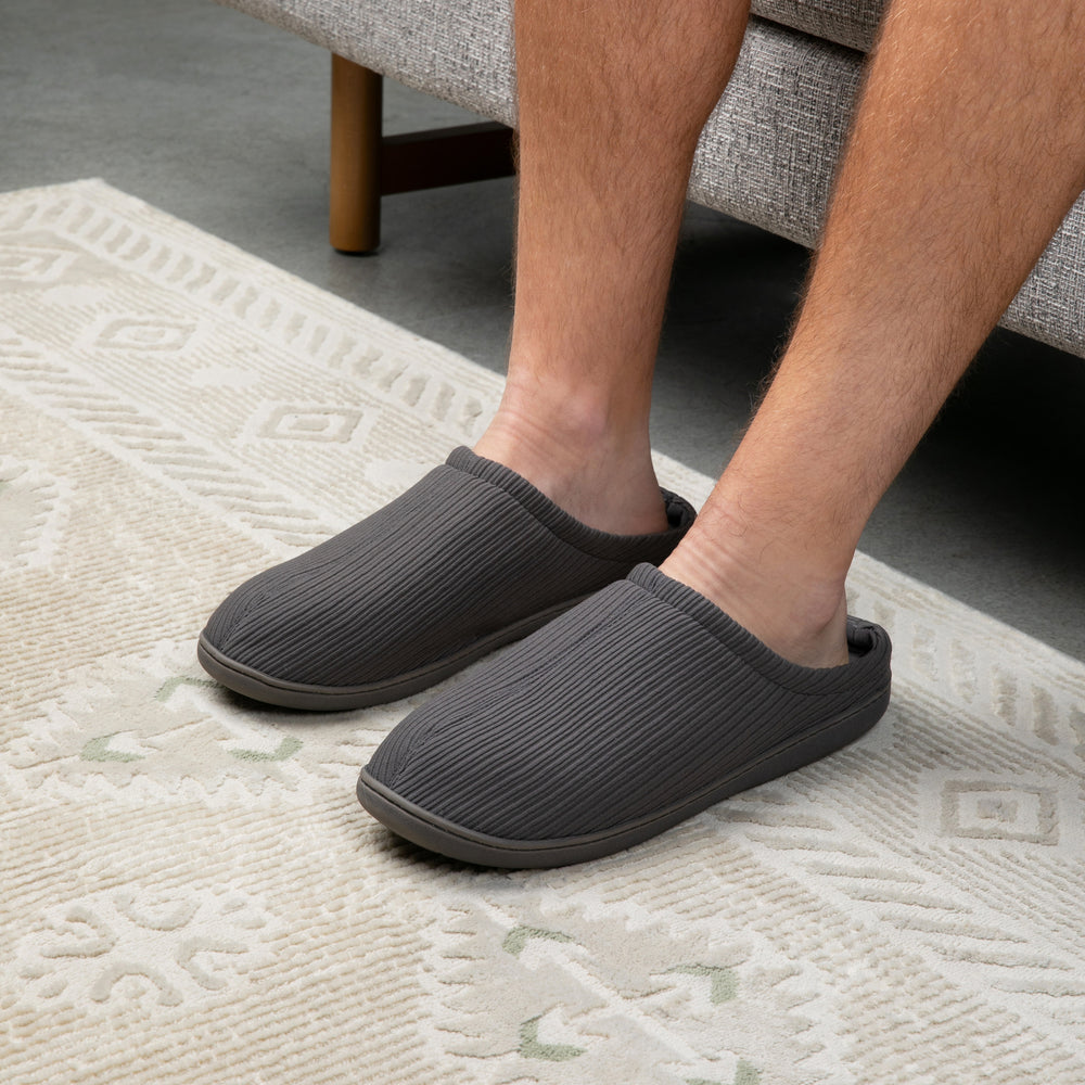 Person wearing gray slippers on a textured rug