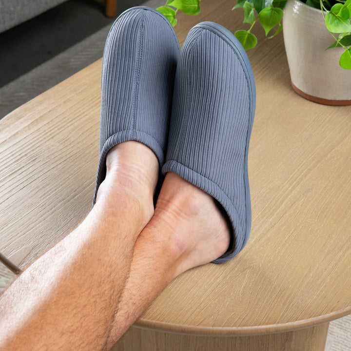 Person wearing blue slippers on a wooden table with a plant in the background