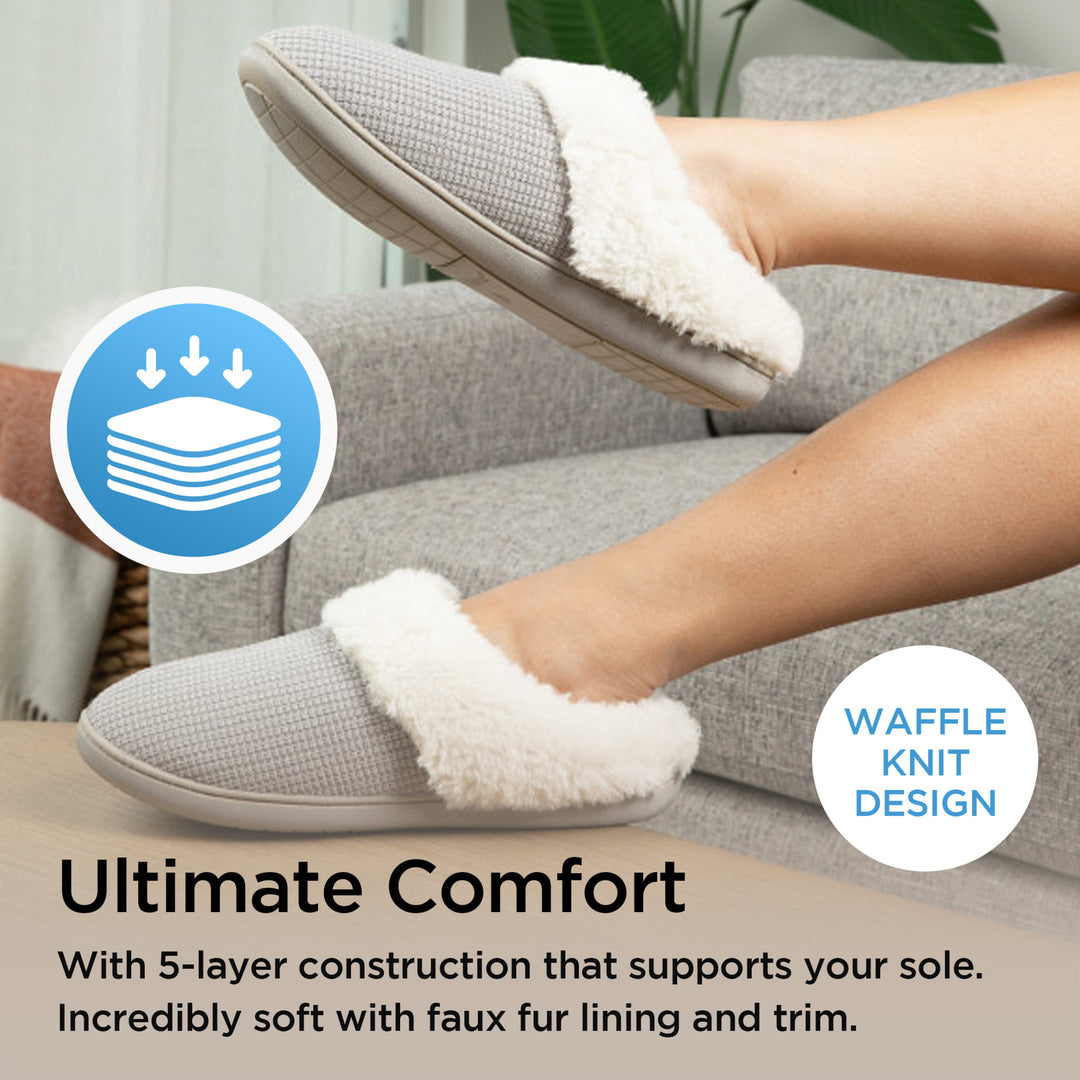 Gray slippers with white fur lining worn by a person sitting on a couch, with text highlighting comfort and waffle knit design.