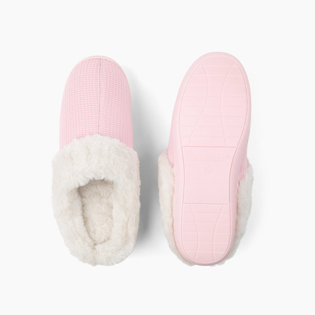 Pair of pink slippers with white fur lining on a light gray background