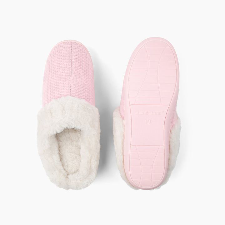 Pair of pink slippers with white fur lining on a light gray background