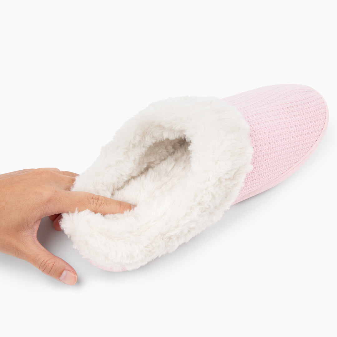 Pink and white slipper with a fluffy interior held by a hand on a white background