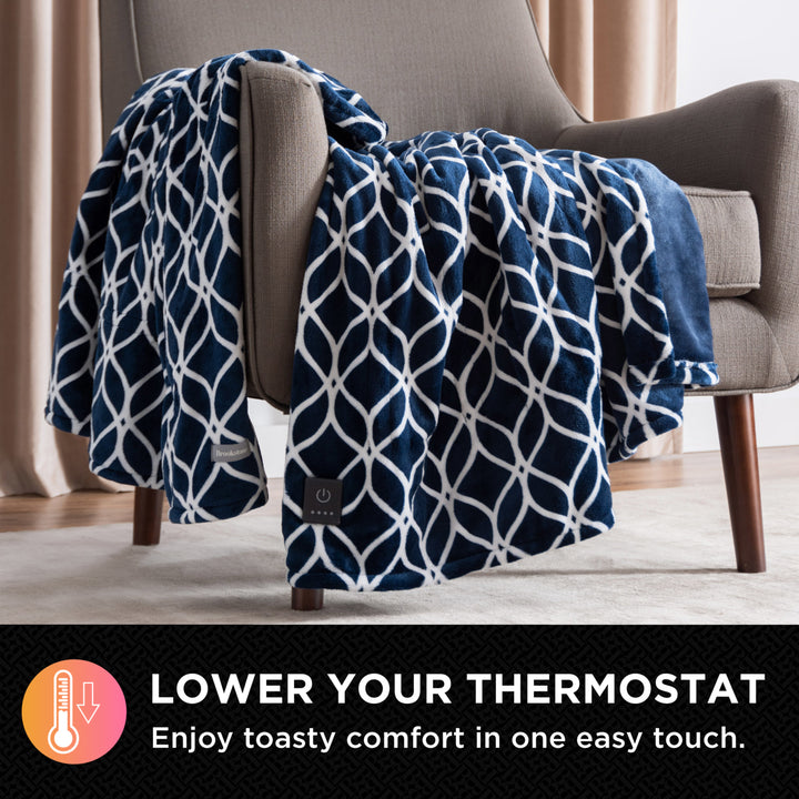 Navy patterned electric blanket draped over a chair with text promoting lowering the thermostat for comfort.