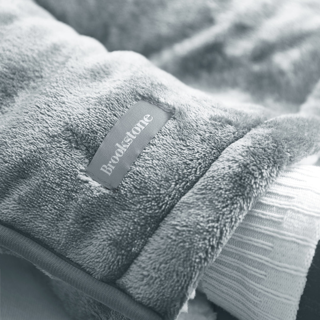 Gray fleece blanket with a Brookstone label on a soft focus background