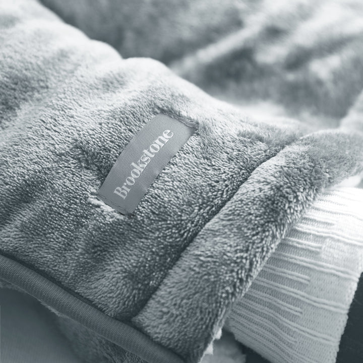 Gray fleece blanket with a Brookstone label on a soft focus background