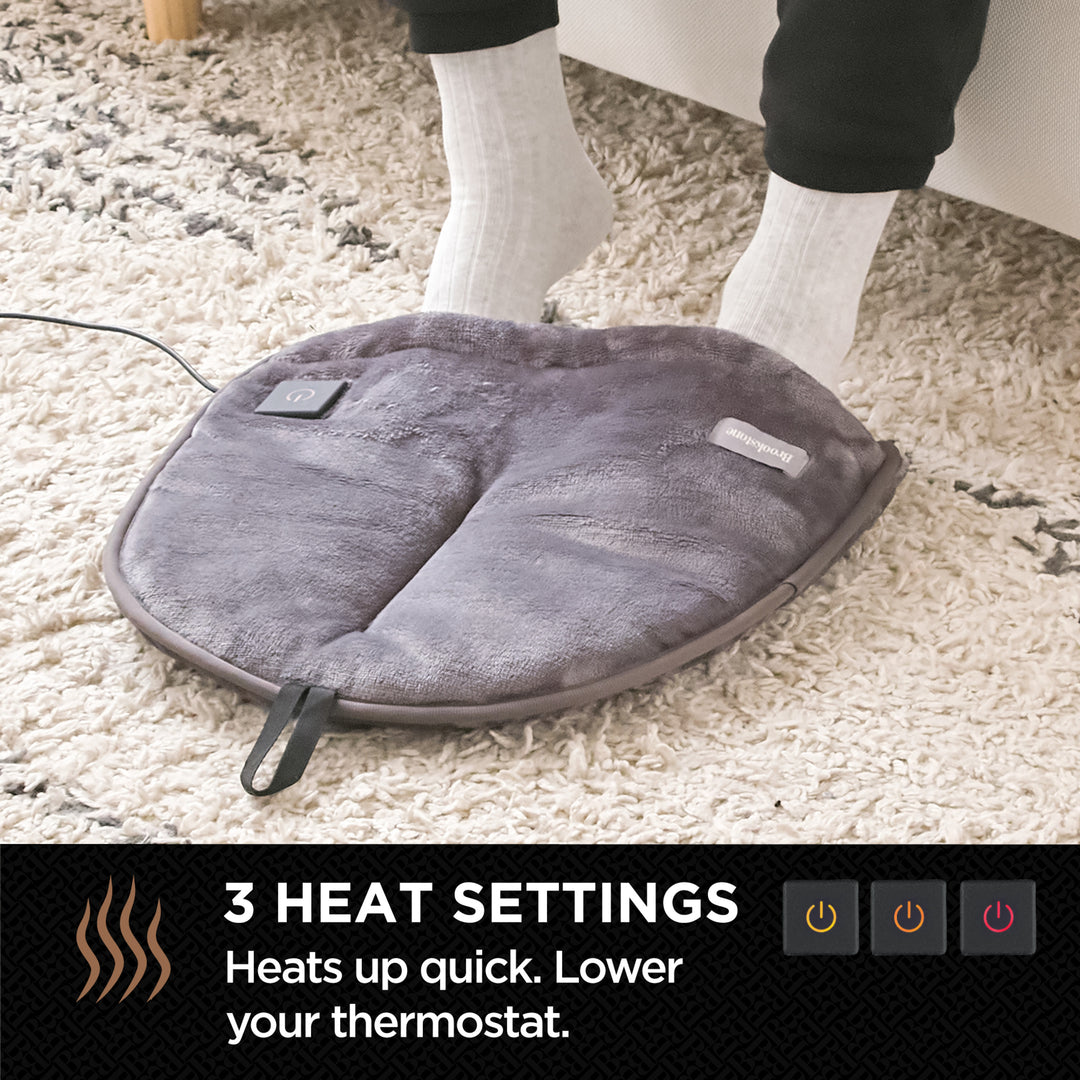 Gray heating pad on a carpeted floor with text about heat settings.