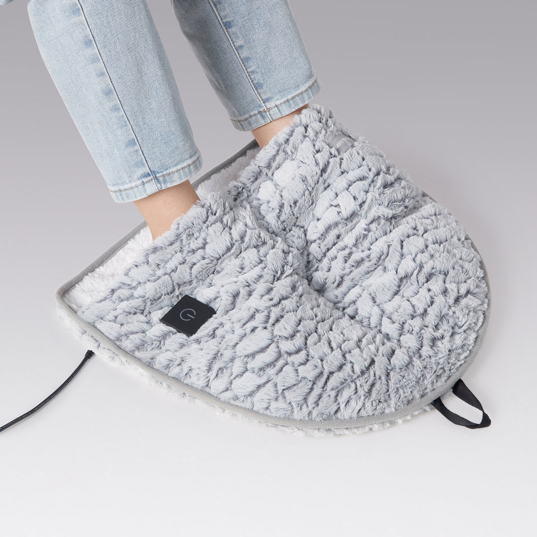 Gray foot warmer being worn with a person's leg in light blue jeans on a gray background