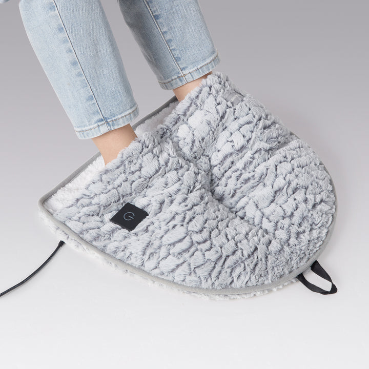 Gray foot warmer being worn with a person's leg in light blue jeans on a gray background