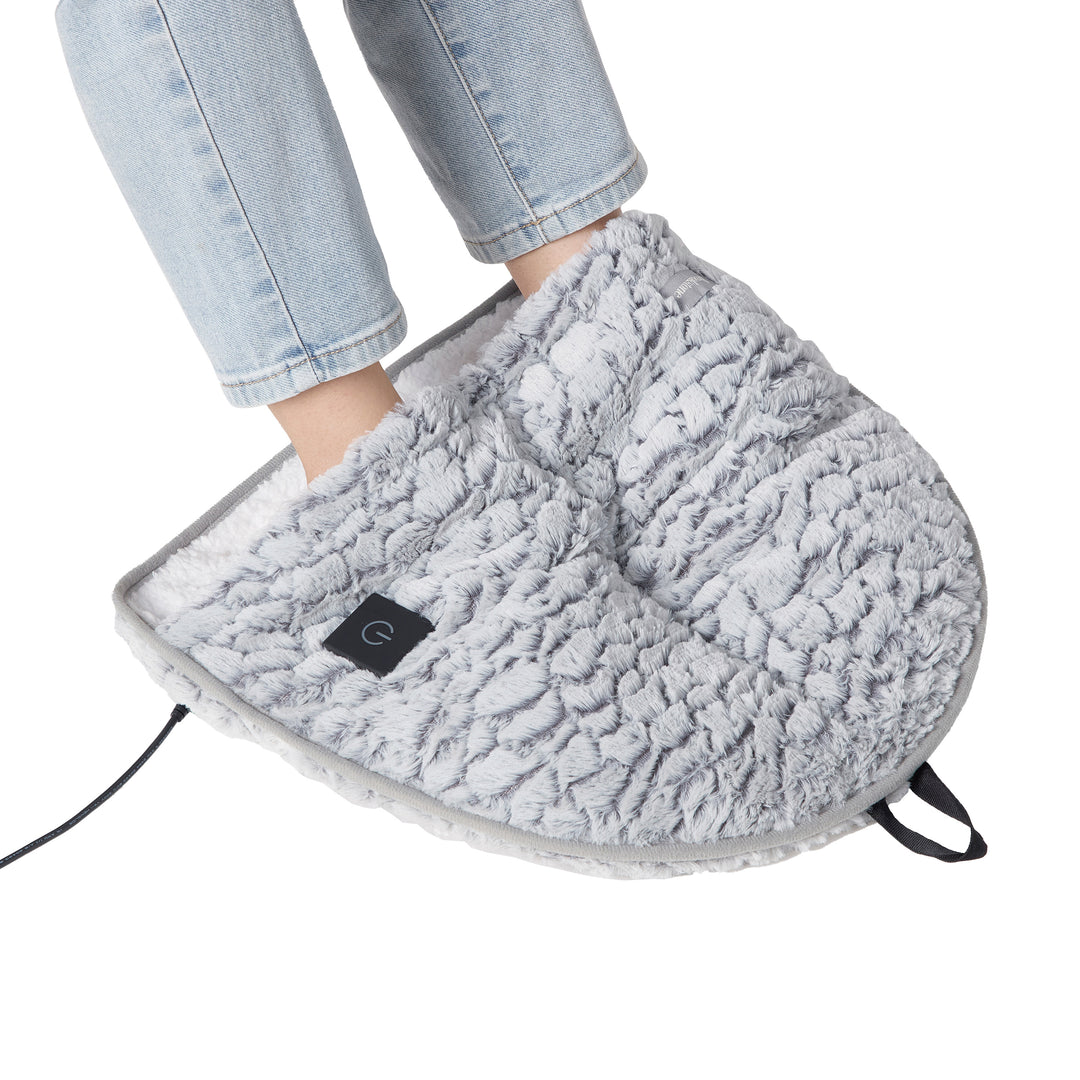 Gray foot warmer being worn with a person's leg in light blue jeans on a white background
