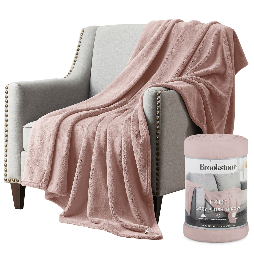 Pink plush throw blanket draped over a gray armchair with a Brookstone package next to it.
