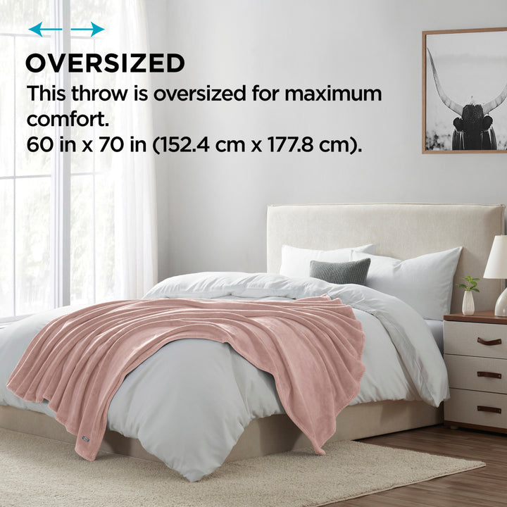 Pink throw blanket on a bed in a bedroom with text indicating oversized size.