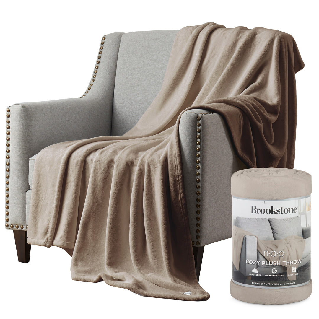 Beige blanket draped over a gray armchair with Brookstone product packaging.
