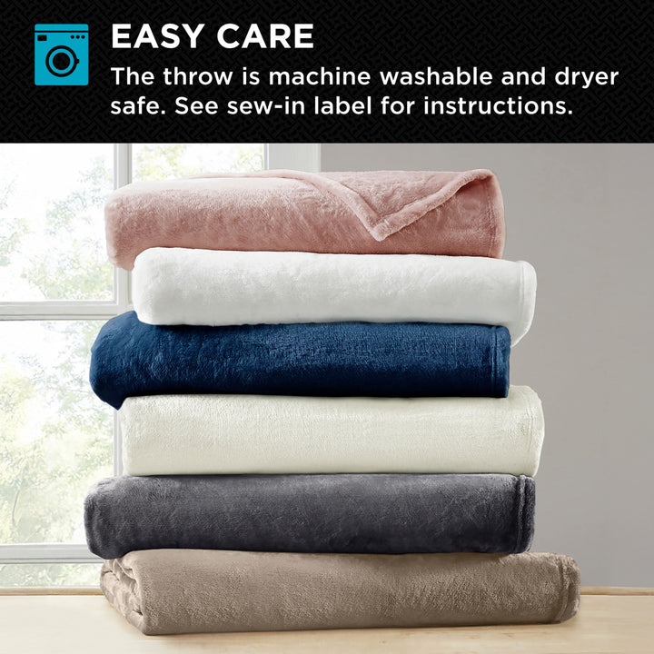Stack of folded blankets in various colors with washing machine icon and text about ease of care.