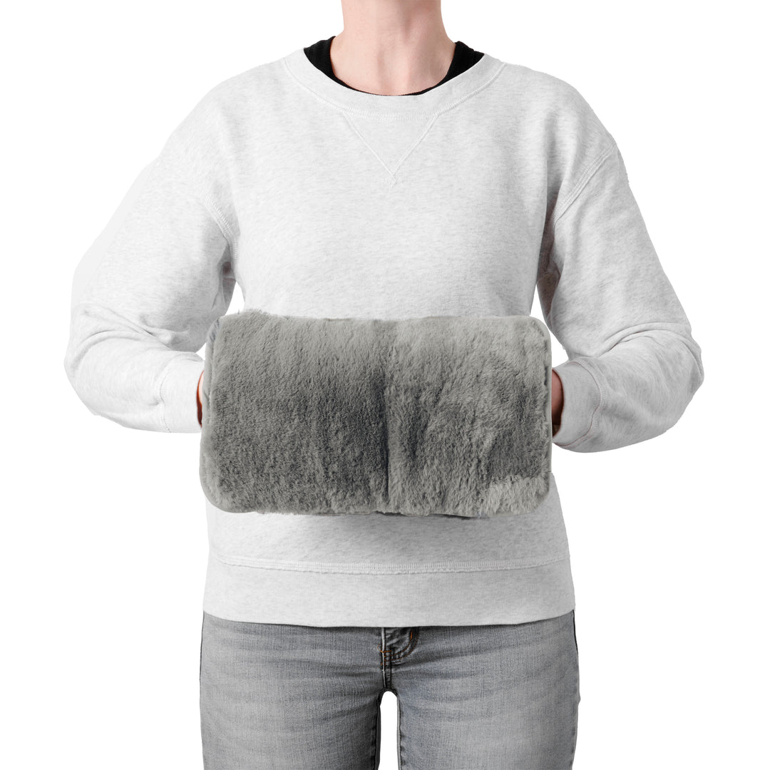 Person wearing a gray sweatshirt holding a gray heating pad.