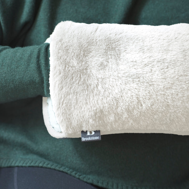 Close-up of a green fleece garment with a white hand warmer and Brookstone label.