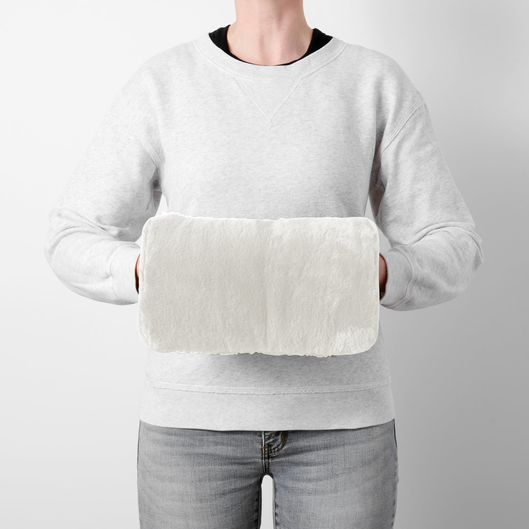 Person holding a white hand warmer against a plain background