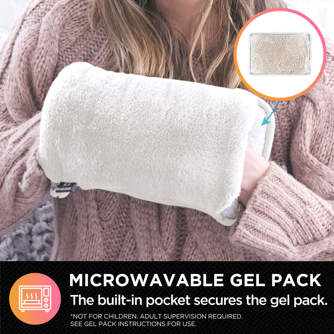 Person holding a microwavable gel pack with a built-in pocket, wearing a pink sweater.