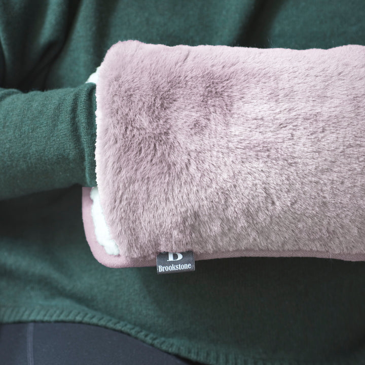 Pink hot water bottle with 'Brookstone' label inside a green garment.