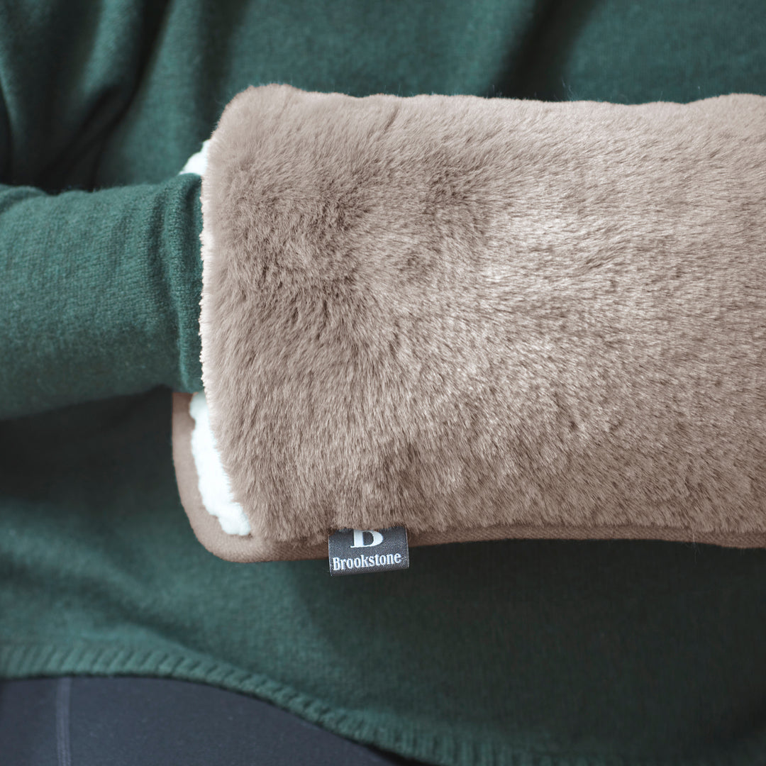Brown plush hand warmer with a Brookstone tag inside a green garment