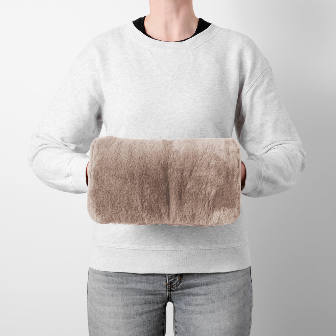 Person holding a hand warmer against a plain background