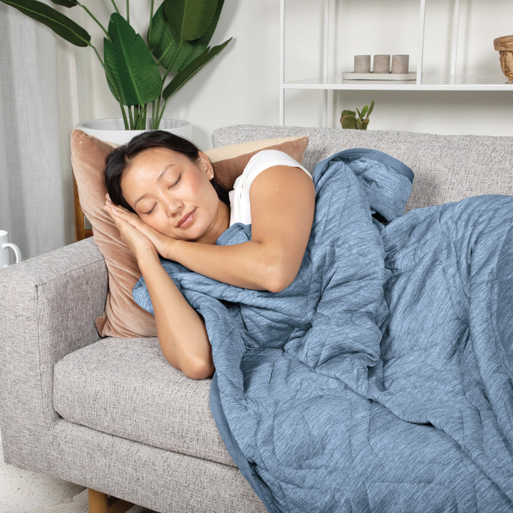 Woman sleeping on a couch with a blue weighted blanket