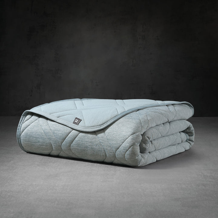 Folded light blue weighted blanket on a dark gray background