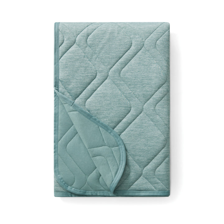 Teal quilted blanket on a white background