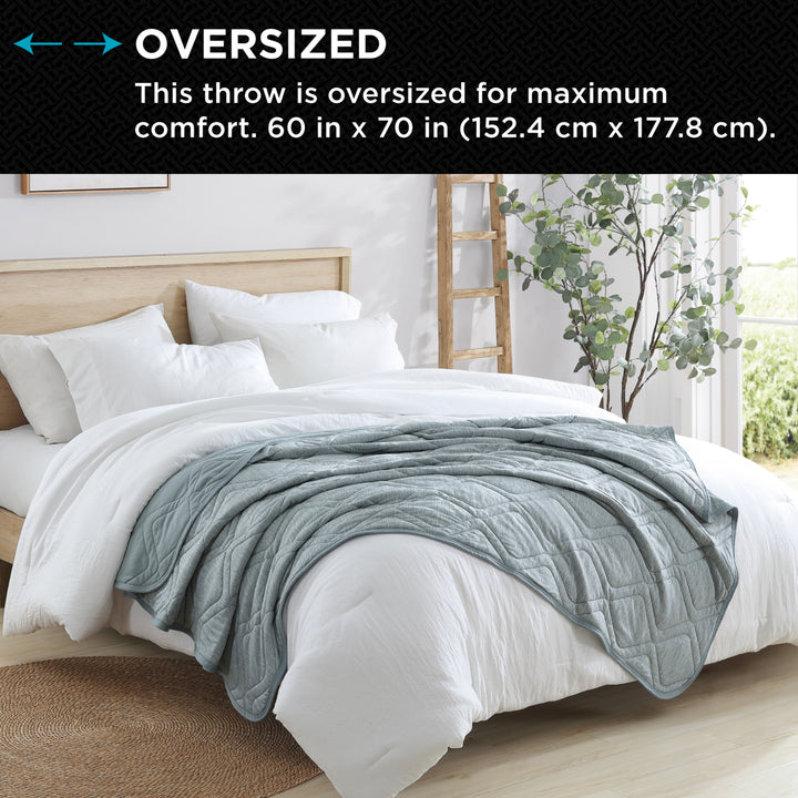 Gray throw blanket on a bed with text indicating oversized size