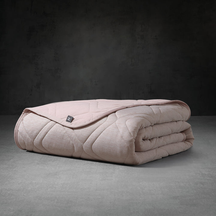 Folded pink blanket on a dark gray surface with a dark gray background