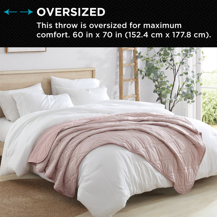 Pink throw blanket on a bed with text indicating oversized size