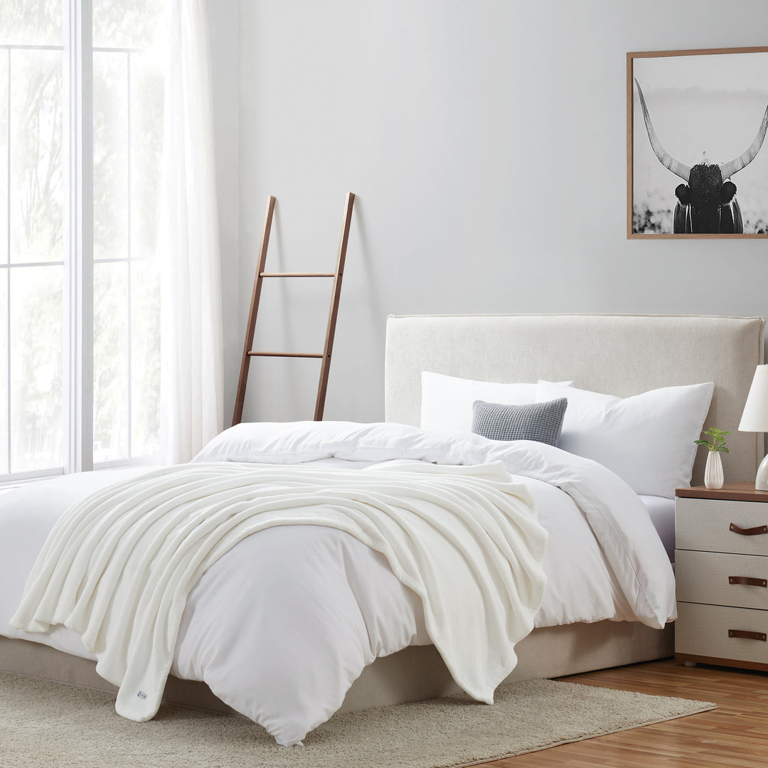 Neatly made bed with white bedding in a bright bedroom