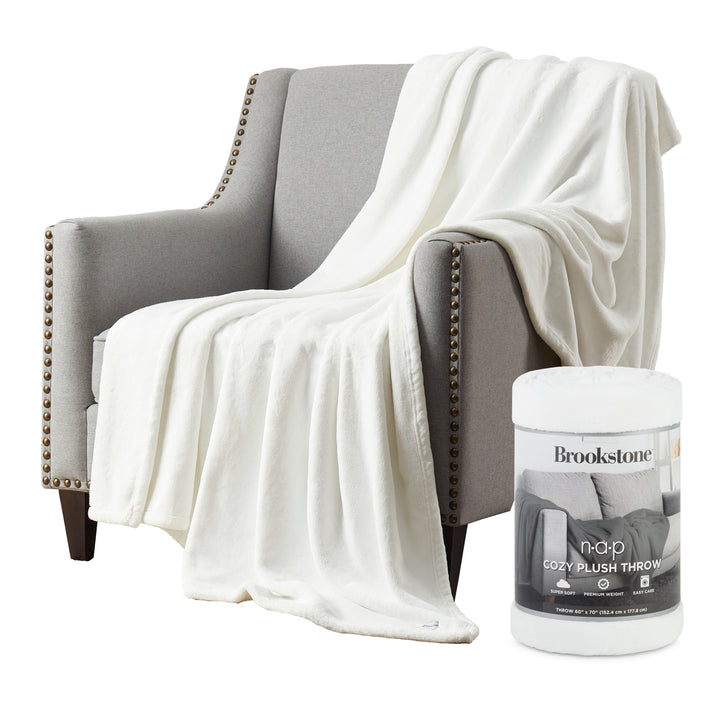White blanket draped over a gray armchair with a Brookstone product container in the foreground.