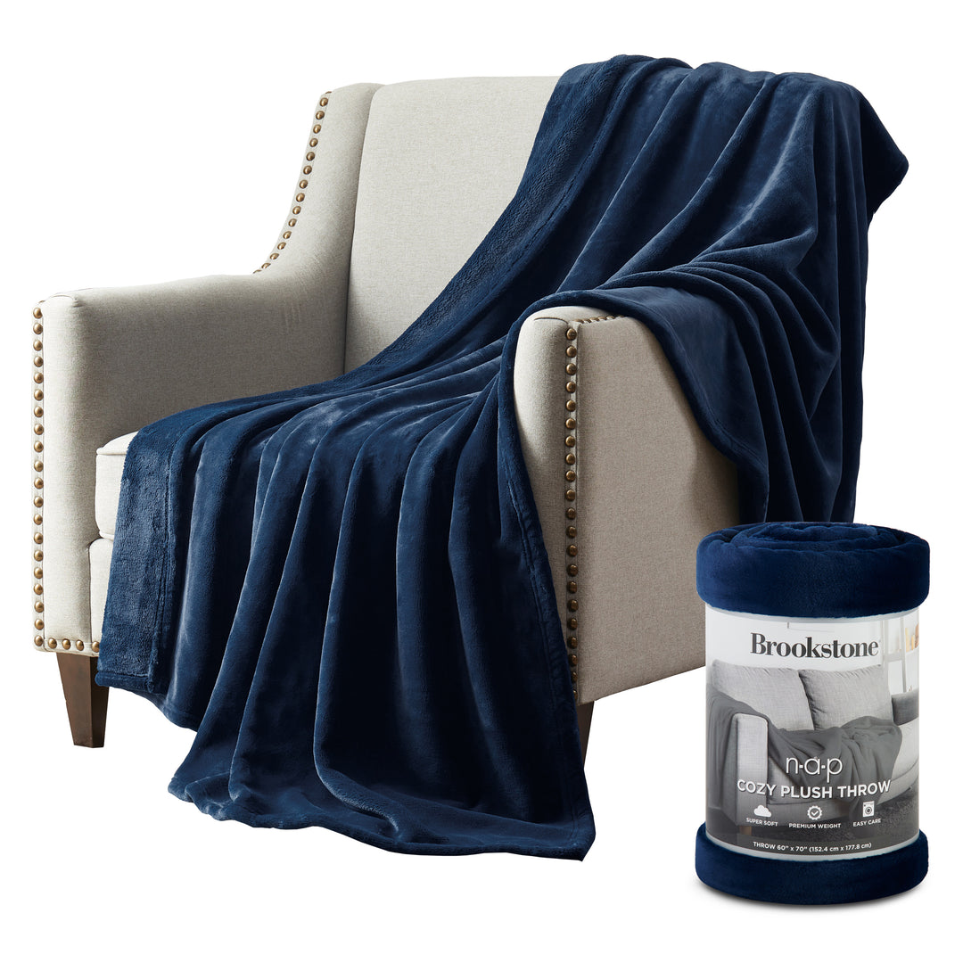 Blue plush throw blanket draped over a beige armchair with a Brookstone product packaging.