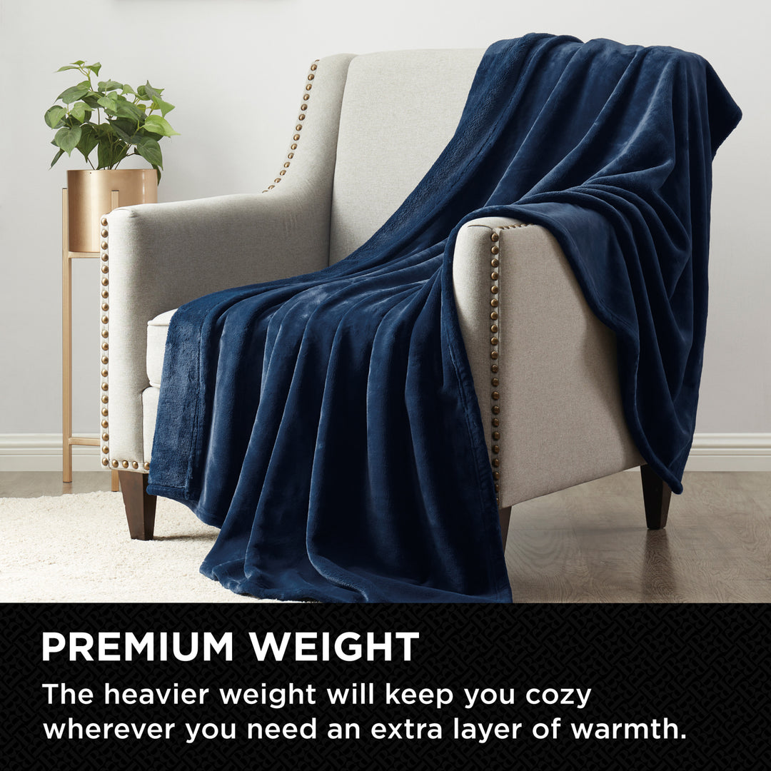 Plush Navy throw blanket draped over a modern armchair in a cozy living room setting.