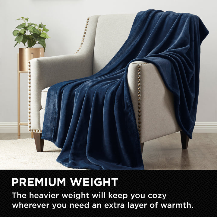Plush Navy throw blanket draped over a modern armchair in a cozy living room setting.