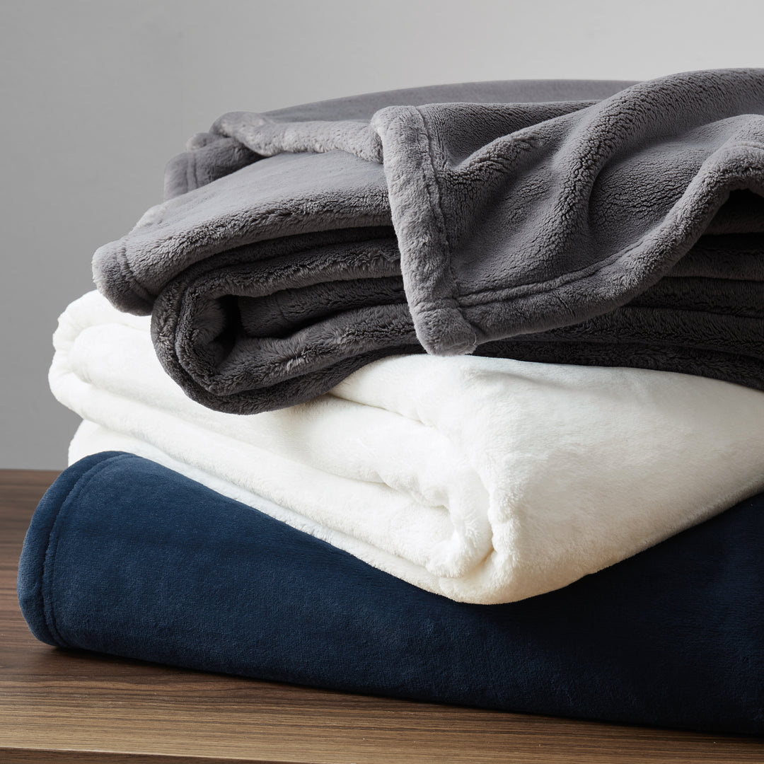 Stack of plush throw blankets in assorted colors showing soft, cozy texture.