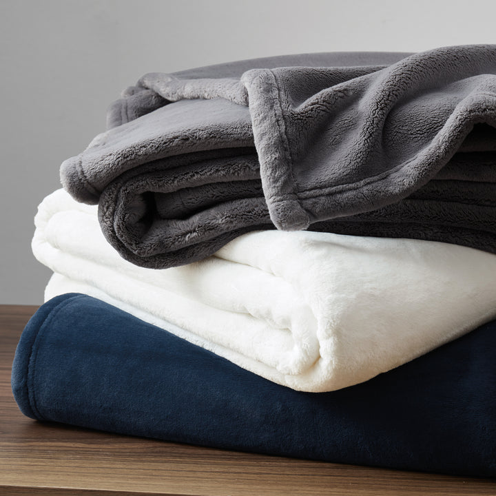 Stack of plush throw blankets in assorted colors showing soft, cozy texture.