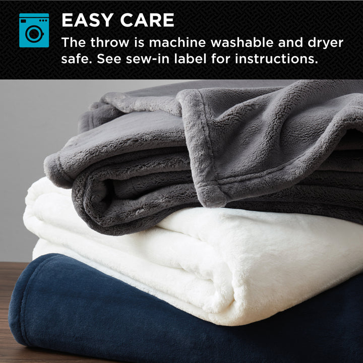 Stack of plush throw blankets in gray, white, and navy, highlighting easy-care machine washable design.