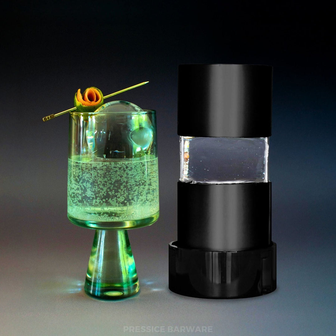 Green cocktail in a glass with a black ice ball press, ice sphere maker by pressice barware on a gradient background