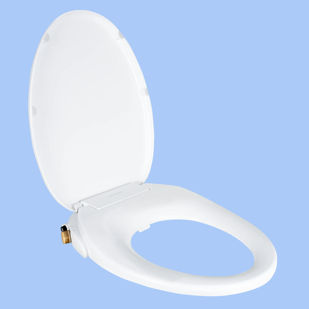 3/4 view White TUSHY Oasis bidet seat, with bamboo control knobs, on a blue background