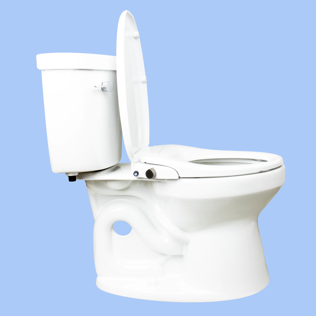 Side view of a toilet with a TUSHY Oasis bidet seat, lid open, with a platinum control knob, on a blue background 