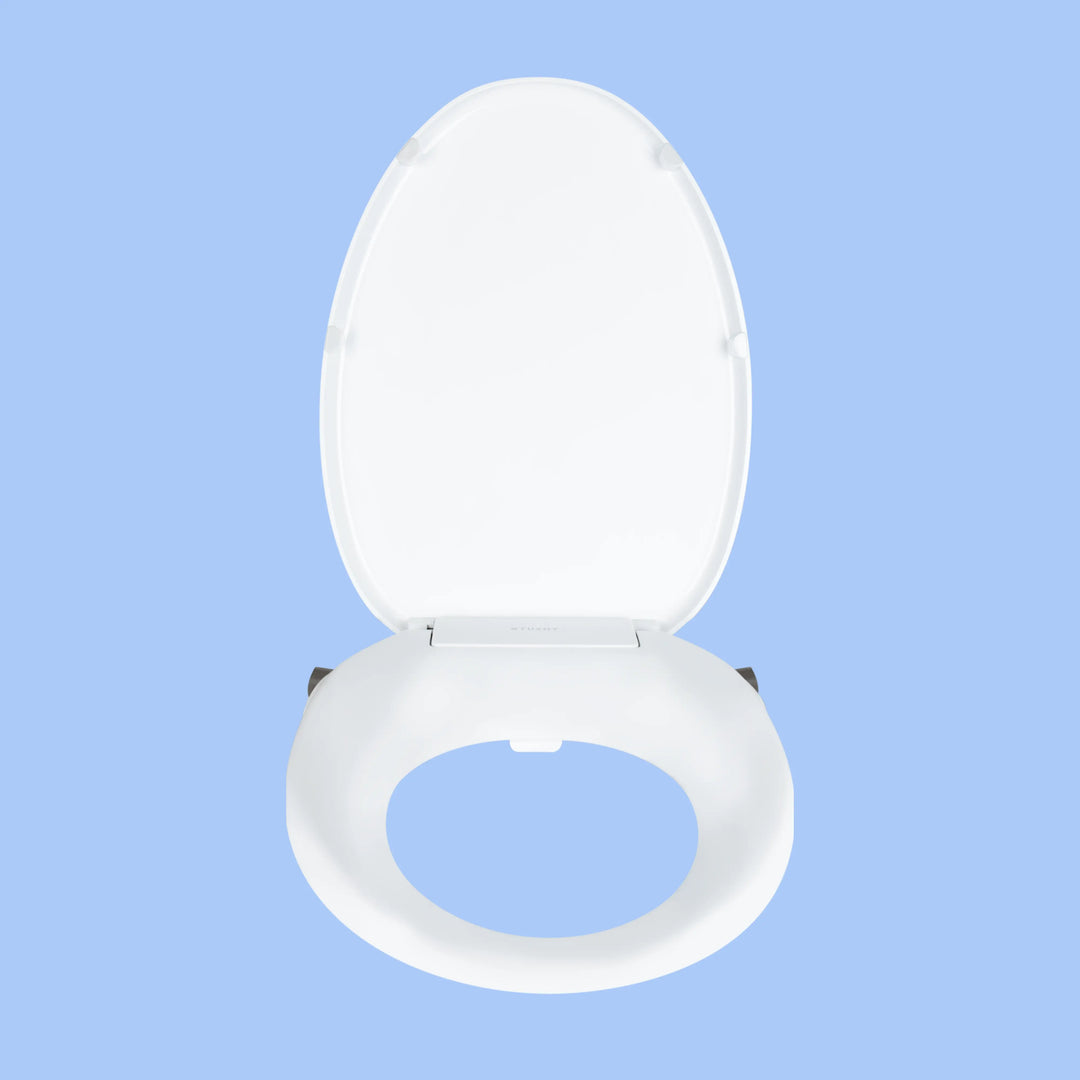 Front view White TUSHY Oasis bidet seat, with platinum control knobs, on a blue background