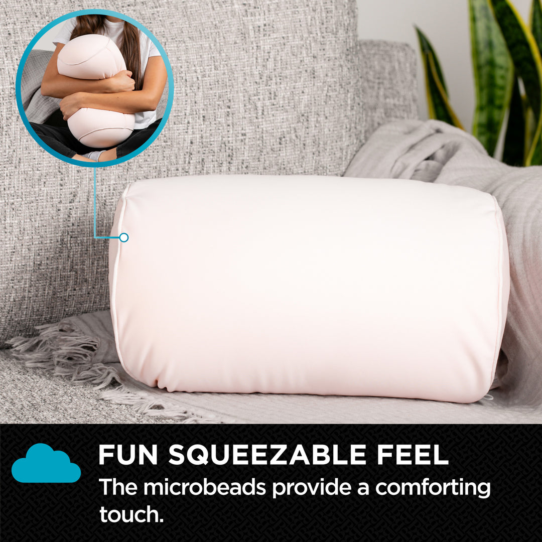 White cylindrical pillow with text about microbeads on a gray couch.