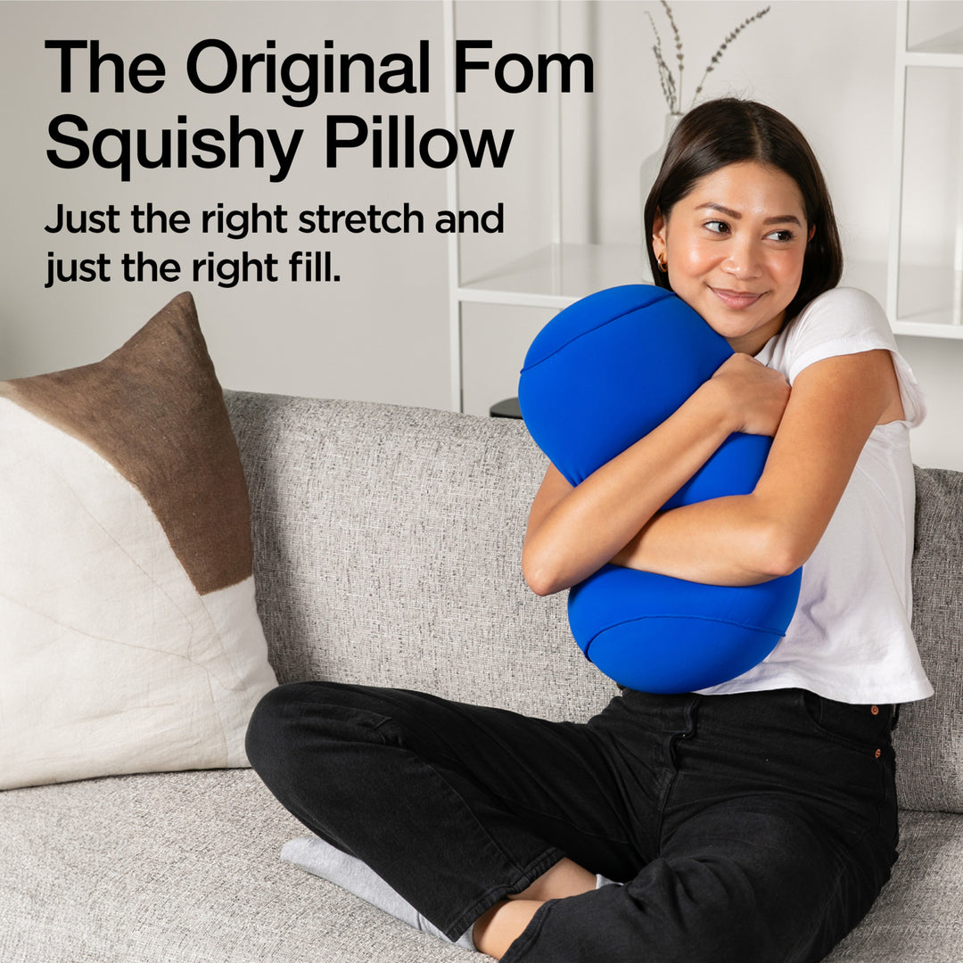 Woman holding a blue squishy pillow with text describing it as 'The Original Fom Squishy Pillow'.