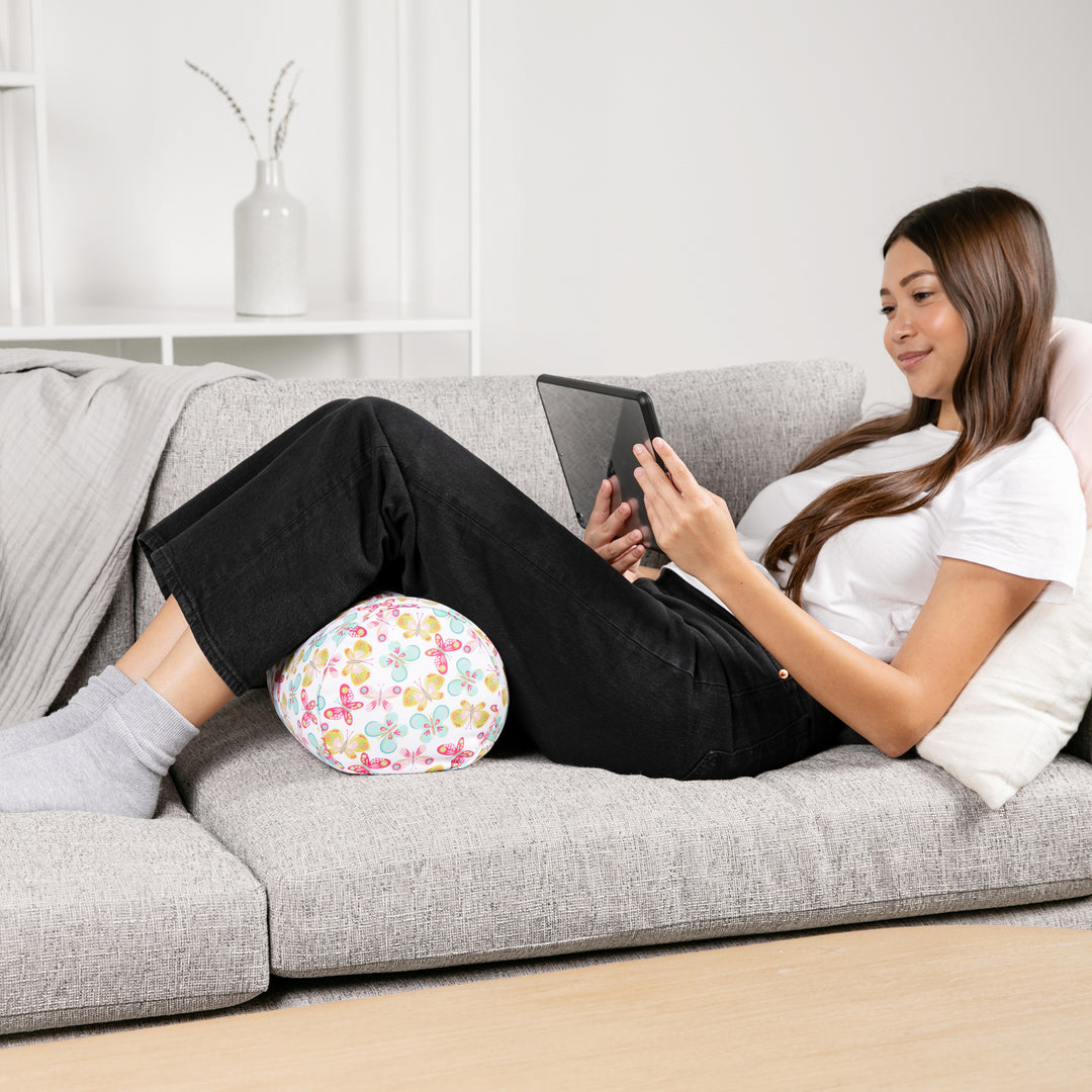 Woman sitting on a couch with a floral ball pillow and using a tablet.