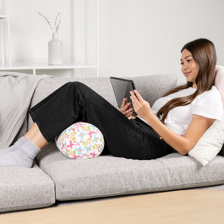 Woman sitting on a couch with a floral ball pillow and using a tablet.