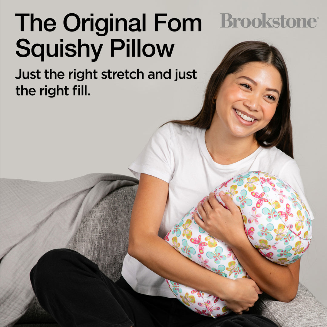 Woman holding a squishy pillow with text about the Original Fom Squishy Pillow by Brookstone.